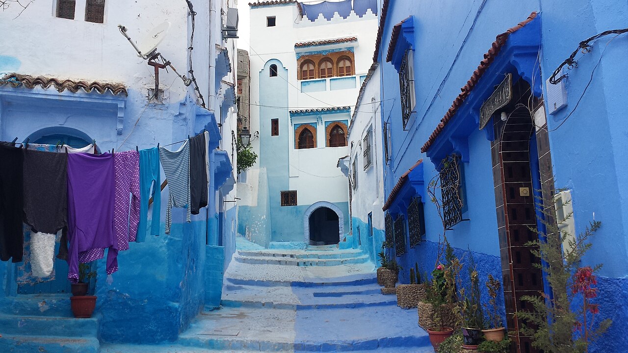 A quiet blue street with laundry and plant pots in Chefchaouen, Morocco